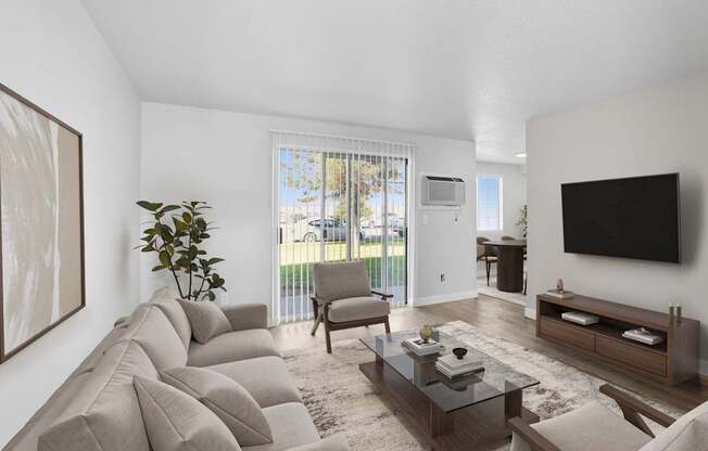 A living room with a large couch, a coffee table, and a flat-screen TV mounted on the wall.