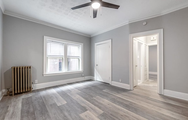 an empty living room with grey walls and a ceiling fan