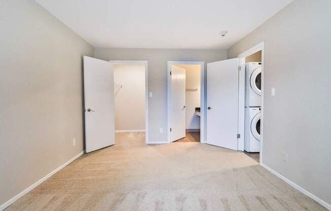 A room with a carpeted floor and three open doors.