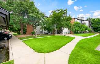 Walkways with beautiful landscaping from covered parking leading to our apartment buildings at Greensview in Aurora, CO