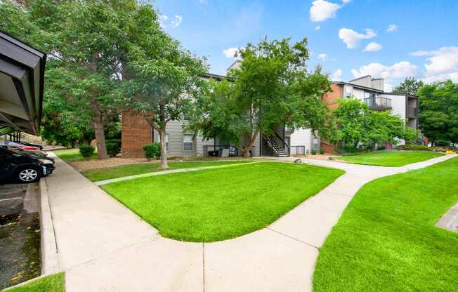 Walkways with beautiful landscaping from covered parking leading to our apartment buildings at Greensview in Aurora, CO