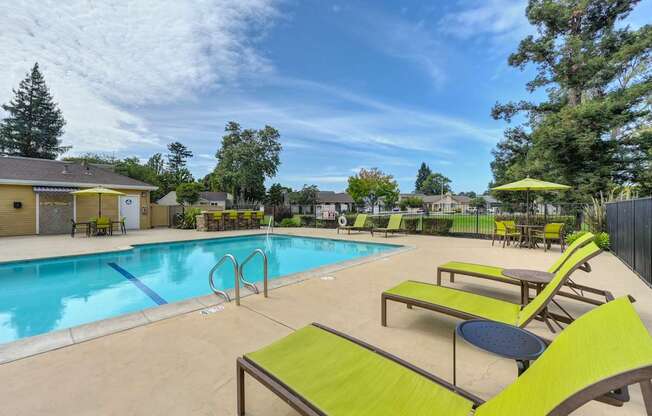A pool area with sun loungers and a yellow umbrella.