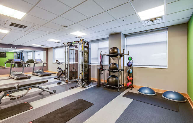 A gym with a variety of equipment including a treadmill, weights, and exercise balls.
