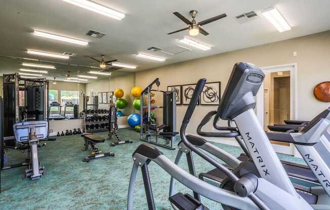 A gym with a variety of equipment including treadmills, weights, and exercise balls.