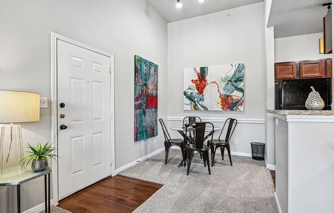 A white door is in a room with a painting on the wall and a table with chairs.
