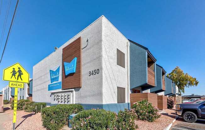 A modern building with a sign that reads "3450" and a school crossing sign in front of it.