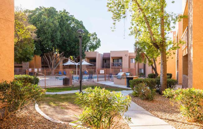 A courtyard with a fence and a tree in front of a building.