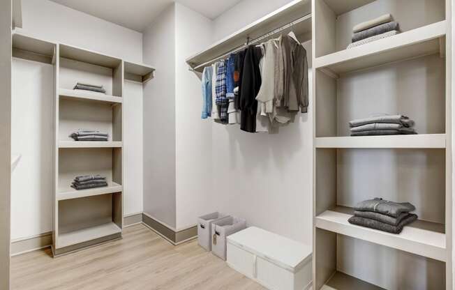 a large walk in closet with shelves and a row of folded clothes