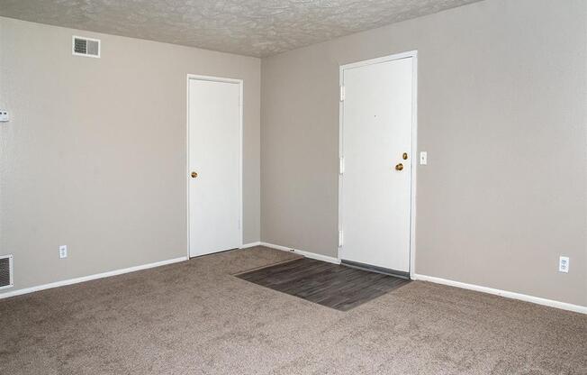 an empty living room with carpet and two doors