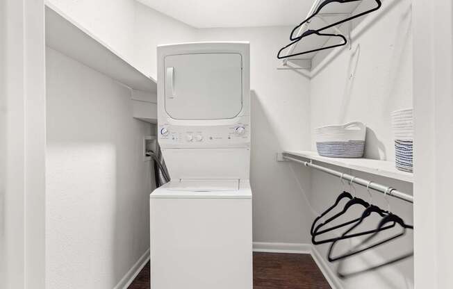 A small white washing machine sits in a laundry room.