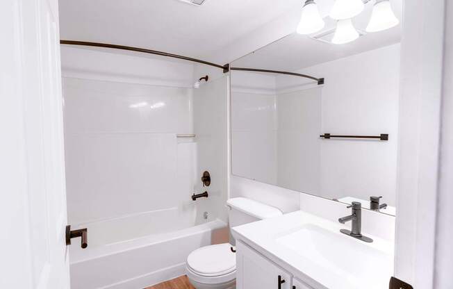 A white bathroom with a toilet, sink, and bathtub.