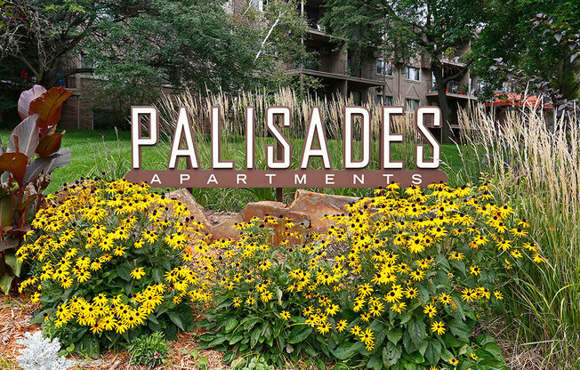 Outdoor monument sign for Palisades Apartments amongst a row of flowers.