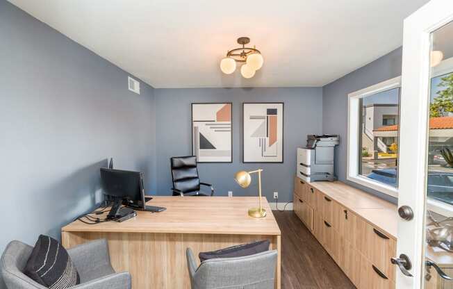 a desk with two chairs and a computer in a room with a window and a door