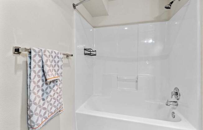 A white bathroom with a white tub and a towel hanging on the wall.