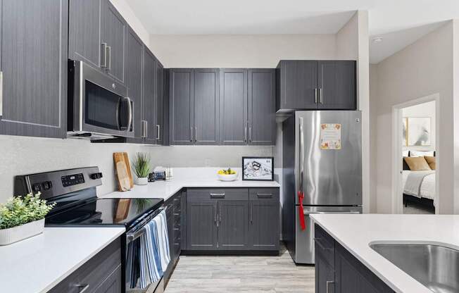A kitchen with dark cabinets and a stainless steel refrigerator.