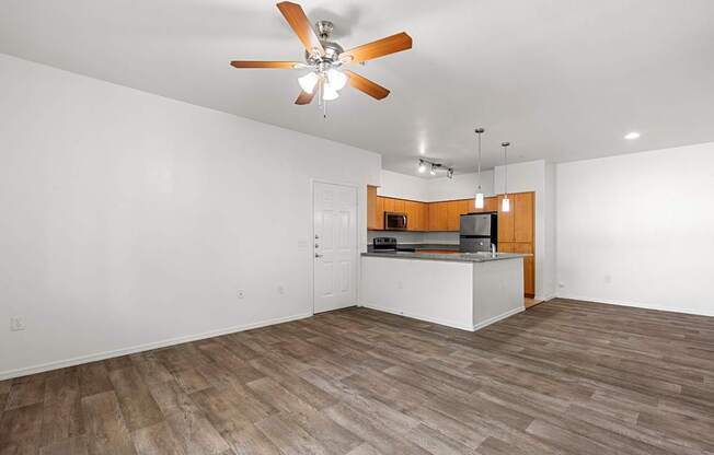 A room with a ceiling fan and a kitchenette.
