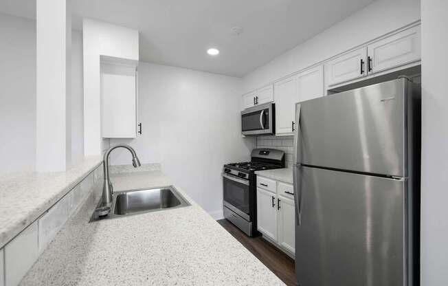 A modern kitchen with a stainless steel refrigerator, microwave, and oven.
