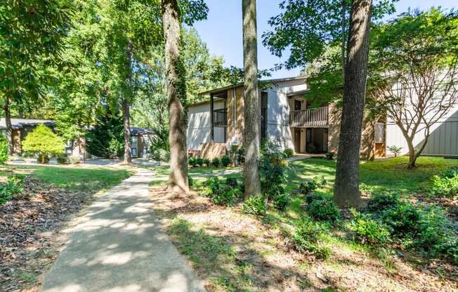 a sidewalk in front of a house with trees