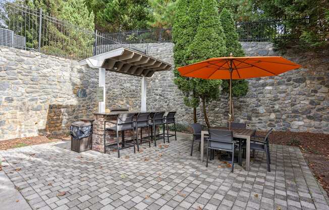 A patio with a table and chairs under an orange umbrella.