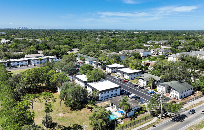 Charming suburban apartment complex surrounded by lush greenery, offering modern living with a pool and ample parking.