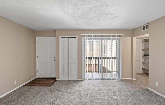 an empty living room with a door to a balcony