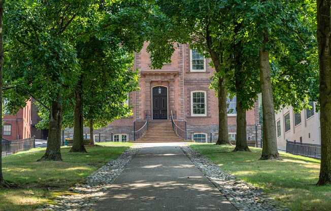 A pathway with trees on both sides leads to a building.