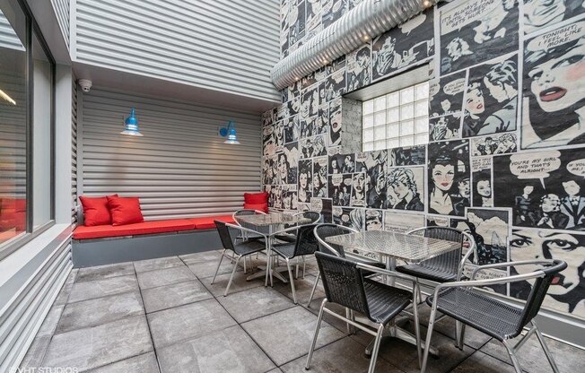 a patio with tables and chairs and a wall covered in graffiti