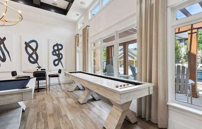 A pool table is in the middle of a room with a wooden floor and a window.