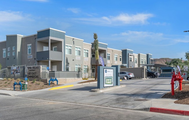 a row of apartment buildings with a parking lot in the foreground at Loma Villas Apartments, San Bernardino, 92408