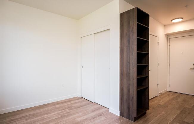 a bedroom with white walls and wood flooring and a close