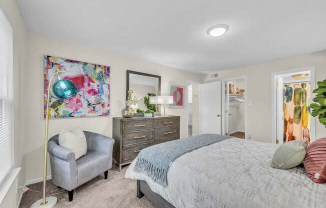 A bedroom with a bed, dresser, and chair.