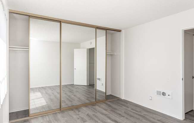 an empty room with white walls and mirrored closet doors