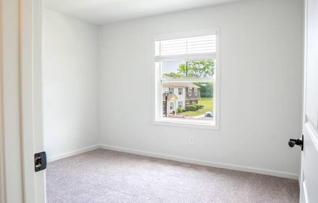 a bedroom with a large window and a carpeted floor