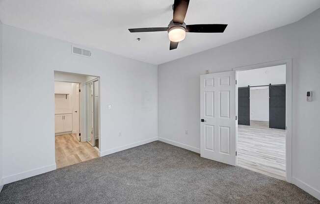 A room with a ceiling fan and carpeted floor.
