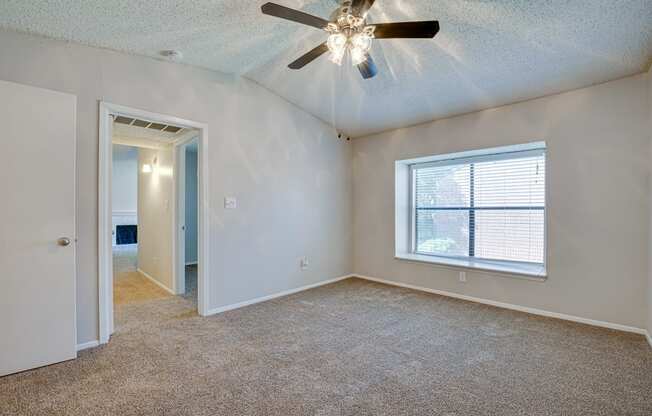 an empty living room with a ceiling fan and a window