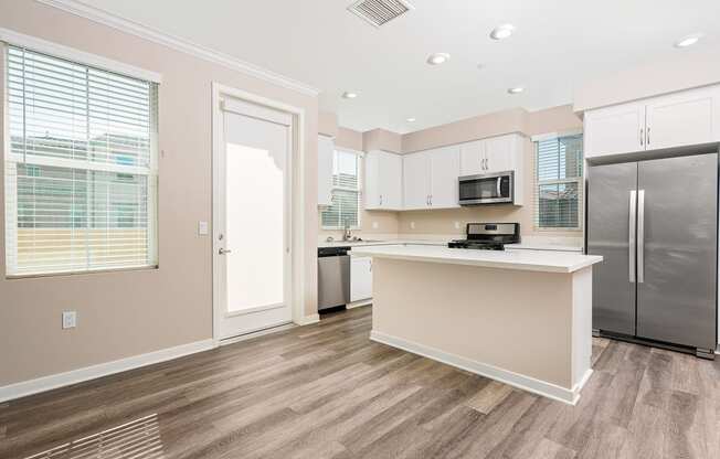 a kitchen with white cabinets, stainless steel appliances and kitchen island