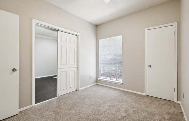 A room with a carpeted floor and a window showing a cityscape.