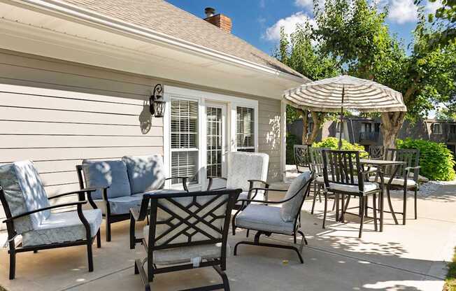 A patio with a table, chairs and an umbrella.