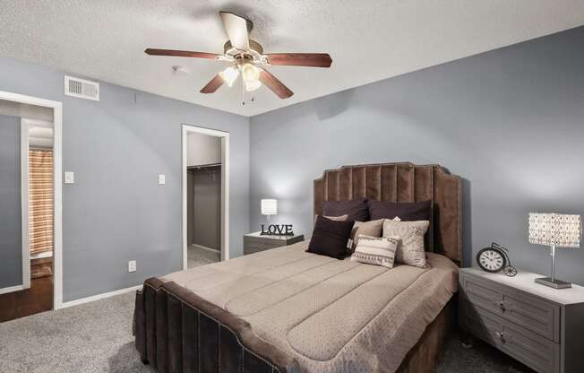 the master bedroom has a king sized bed and a ceiling fan