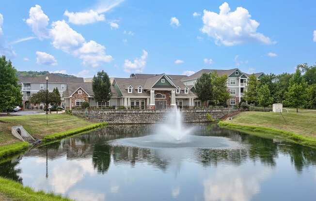 a pond with a fountain in front of a building