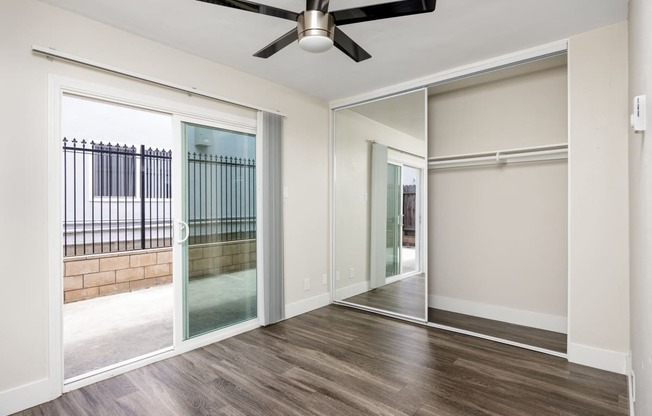 an empty living room with sliding glass doors and a ceiling fan