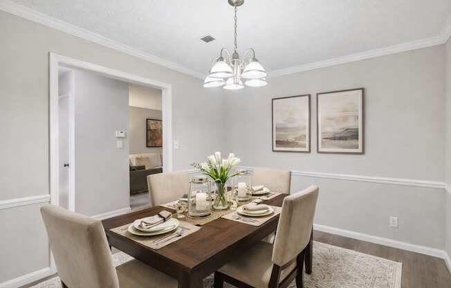 A dining room with a table set for two and a chandelier hanging from the ceiling.