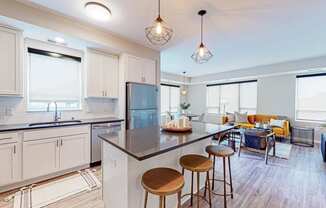 a kitchen and living room with white cabinets and a large island with stools