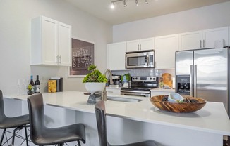 an open kitchen with a large counter with chairs