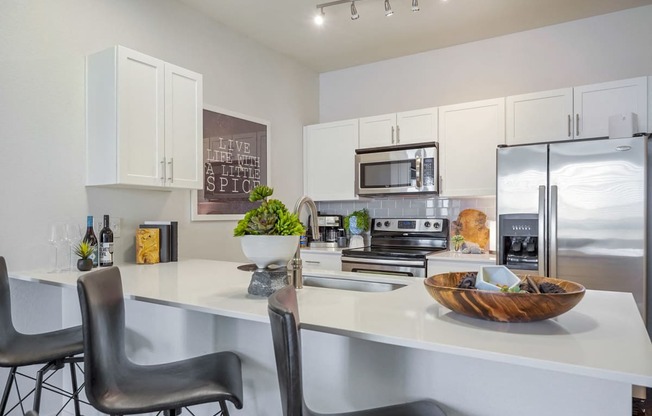 an open kitchen with a large counter with chairs