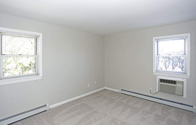 A room with a window and a carpeted floor.