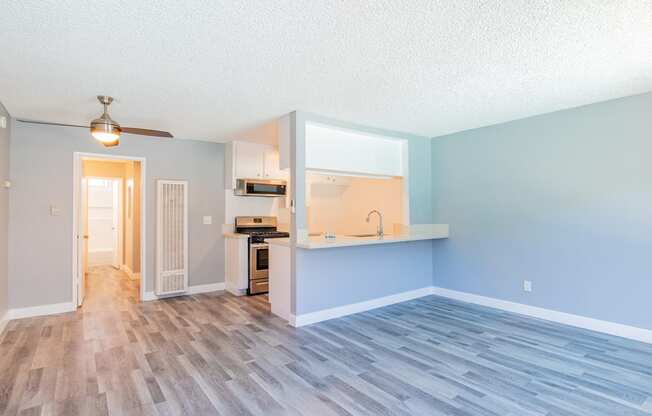 an empty living room and kitchen with a hard wood floor