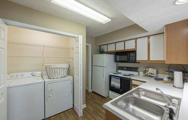 a kitchen with a washer and dryer and a sink and a refrigerator