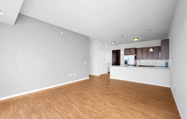 A spacious room with wooden flooring and white walls.