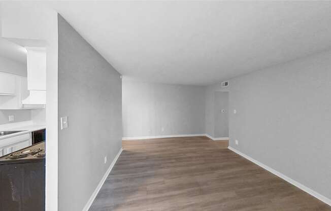 the living room and kitchen of an apartment with grey walls and wood flooring